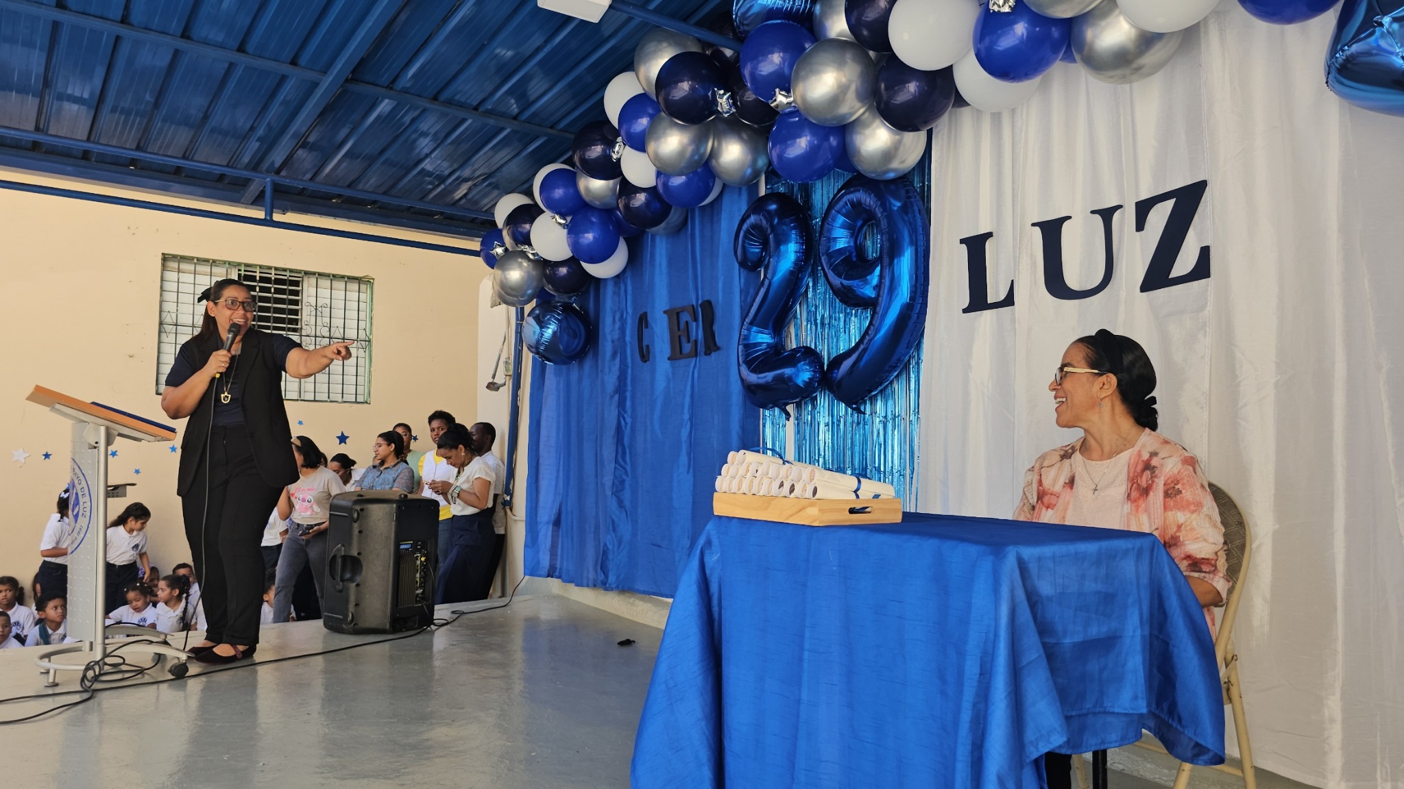 Participantes del acto del 29.º aniversario de CERLUZ en el escenario con decoración azul y plateada